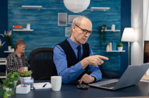 Homme senior travaillant sur un ordinateur dans un bureau moderne, illustrant la réflexion sur la personnalisation de l’expérience client digitale.