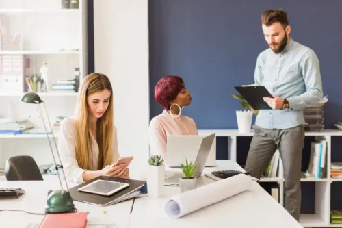 Trois collègues discutent stratégie digitale dans un bureau moderne, illustrant la collaboration autour de l’optimisation de l’acquisition de trafic web.