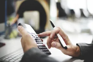 Close-up d’une personne utilisant une calculatrice et un stylo, illustrant la mise en place d’une solution BI standardisée pour le pilotage commercial et financier.

