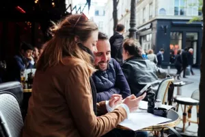 Deux personnes consultant un e-shop sur smartphone à la terrasse d’un café, illustrant l’expérience d’achat multicanale