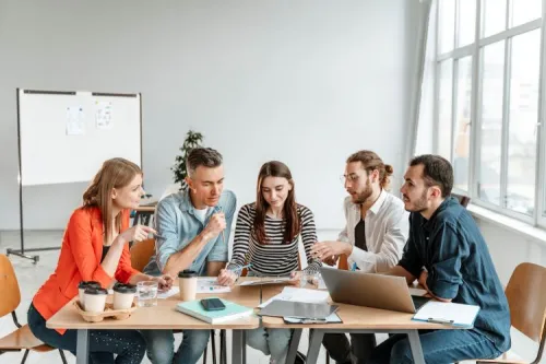 Cinq collaborateurs échangent autour d’un ordinateur et de documents marketing, illustrant la réflexion stratégique des opérateurs sur le marché du travel retail.

